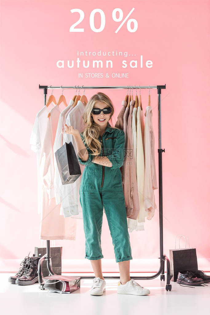 穿着时装和墨镜的时髦儿童站在商店服装和鞋铺边购物袋旁边图片