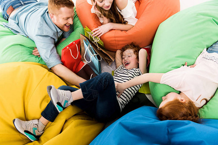 在豆袋椅上玩得开心的购物袋家庭幸福的图片
