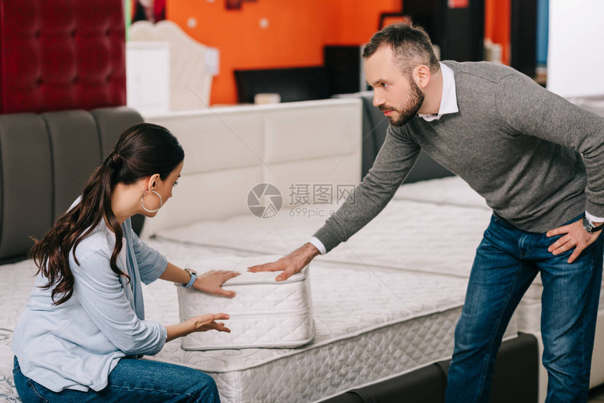 夫妻双方在家具店中选择叠床垫并图片