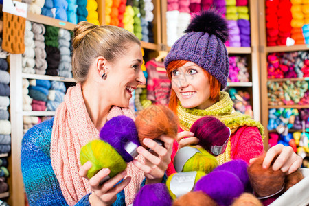 年轻妇女在编织店购买彩色羊毛和纱布作图片