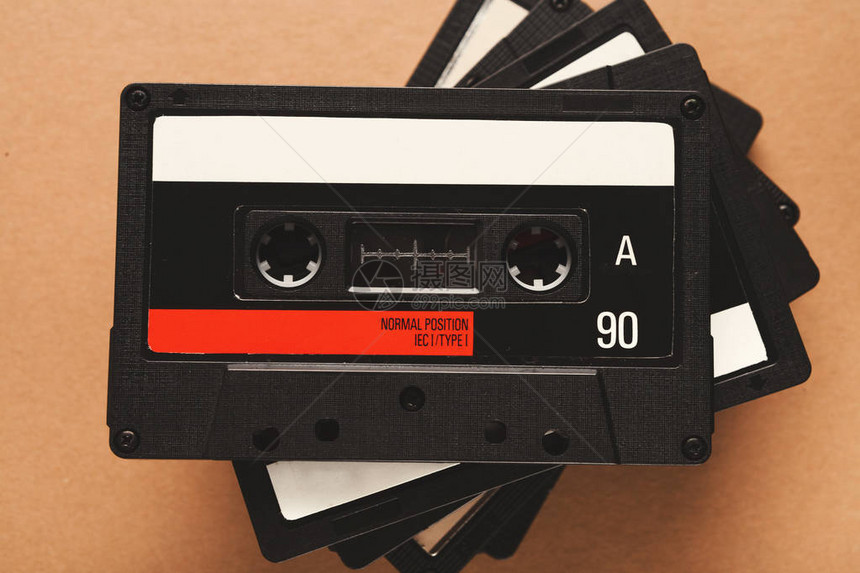 光棕背景的复古录音磁带堆叠式盒装在旧媒体设备堆放上顶部视图图片
