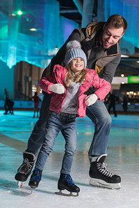 快乐的父亲拥抱可爱的小女儿在滑图片