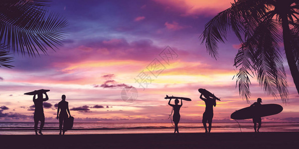 冲浪者在日落海滩上携带冲浪板的轮廓图片