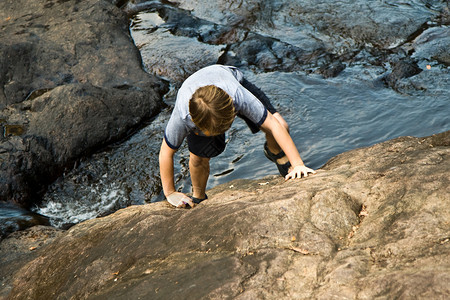 小男孩爬上岩石图片