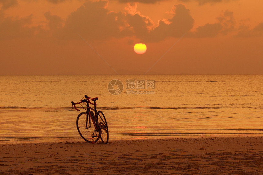 金色夕阳背景下沙滩上自行车的剪影图片