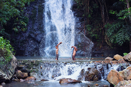 两个男孩在泰国的瀑布乡下玩耍和笑着钓鱼在美丽背景的小溪里钓图片