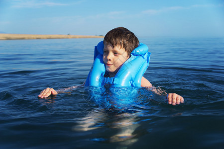 穿着救生衣游泳的微笑男孩高清图片
