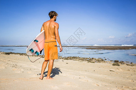 夏日冲浪者站在沙滩上的冲浪板后视图图片