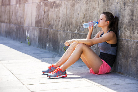 口渴的女慢跑者在训练后喝淡水和选址年轻的运动女子在图片