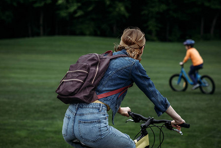 手背着自行车在公园骑自行图片