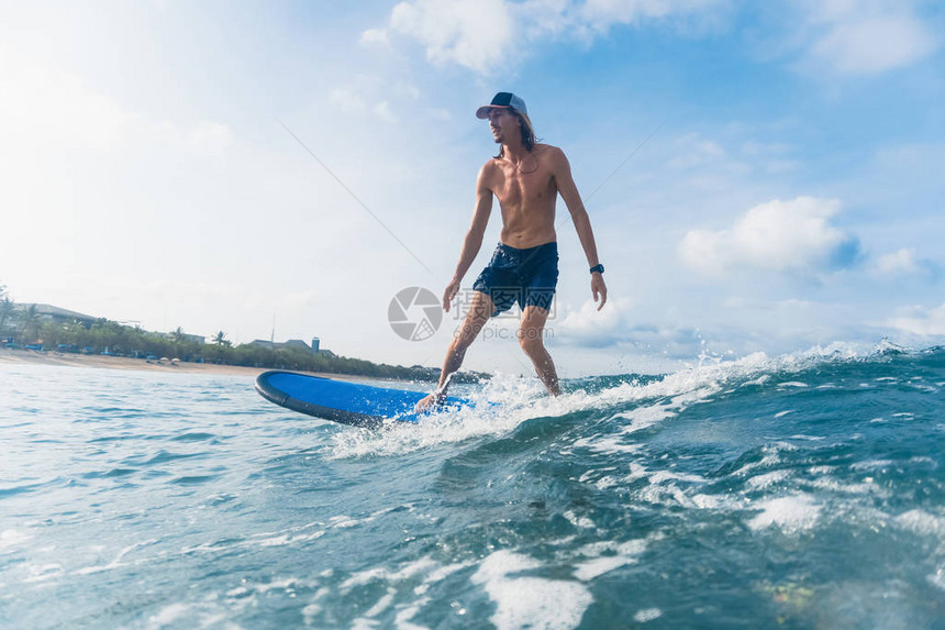 在游泳短裤和海帽冲浪的海洋中图片