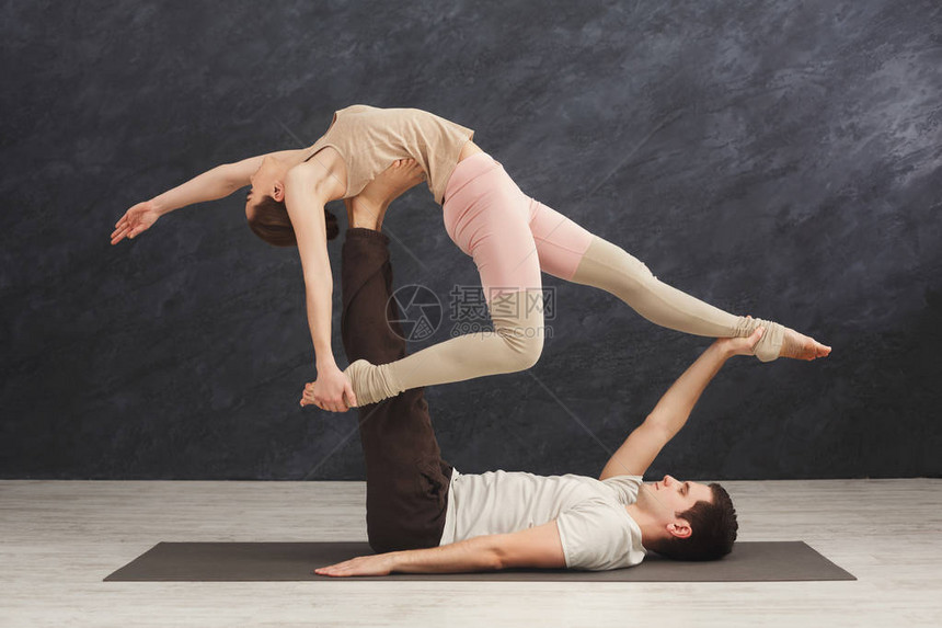 年轻夫妇一起在健身房的垫子上练习杂技图片