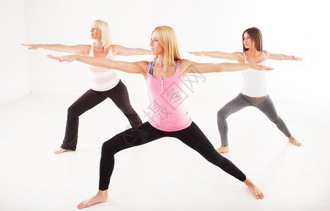 做瑜伽战士II姿势的三个美女图片