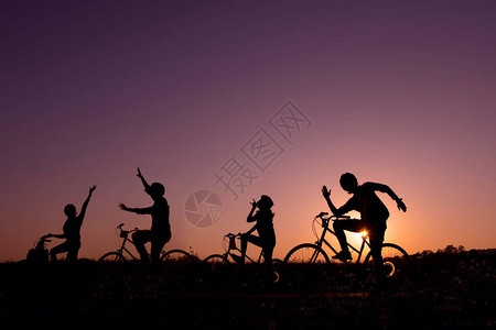 自然日出或日落中不同姿势骑自行车的快乐朋友的剪影年轻和友谊的图片