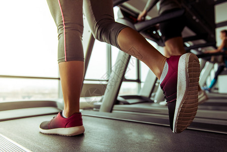 在健身房的跑步机上跑步的女人的腿特写图片