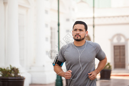 一位英俊的西班牙裔年轻人在城里户外跑步图片