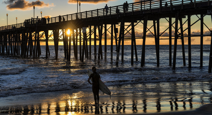 拿着冲浪板的剪影冲浪者在加利福尼亚州欧申赛德的欧申赛德码头观看美丽的日落欧申赛德位于加州西海岸圣地亚哥以北图片