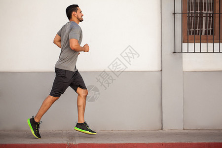 一名运动青年男子在城里跑步和工作的全部肖图片