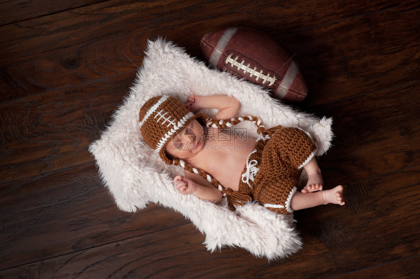 一个12天大的新生儿男孩睡在皮草板箱里穿着一个被编织图片