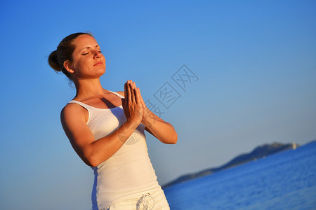 在海滩上的瑜伽冥想中的年轻女子图片