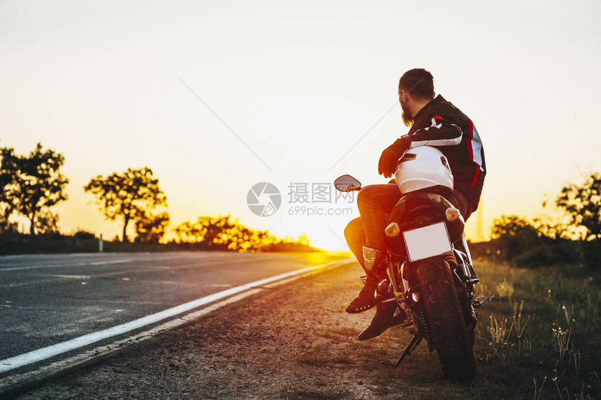一个留着胡子的骑自行车的人坐在他的摩托车上图片