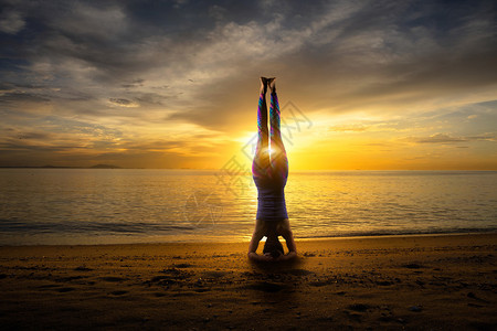 在海岸的日落瑜伽妇女倒立图片