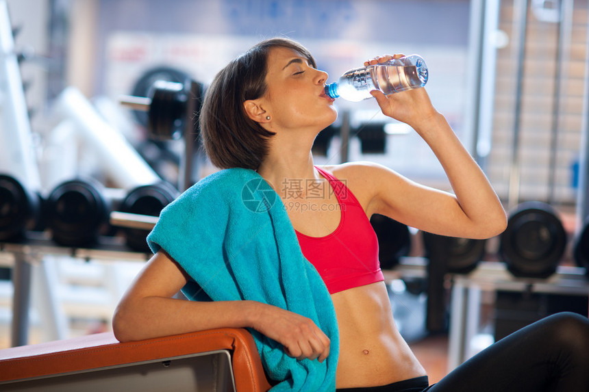 健身房里的女人从水瓶里喝水图片