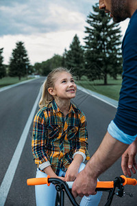 父亲教他快乐的女儿如何骑单车并教他图片