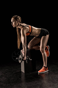 站在膝上和用哑铃锻炼的年轻运动女图片