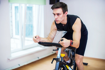 运动员在健身房骑自行车锻炼他的腿做心背景图片