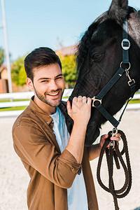 手持马架和在牧场看摄影机的男子骑马人笑着微笑图片