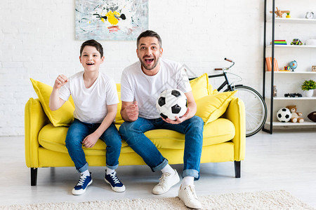父亲和儿子在看沙发体育比赛时欢呼在家图片