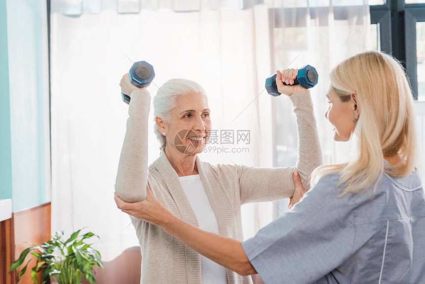 护士帮助在养老院里微笑的老年妇女与图片
