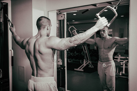 肌肉男健美运动员在健身房训练和摆肌肉背景图片