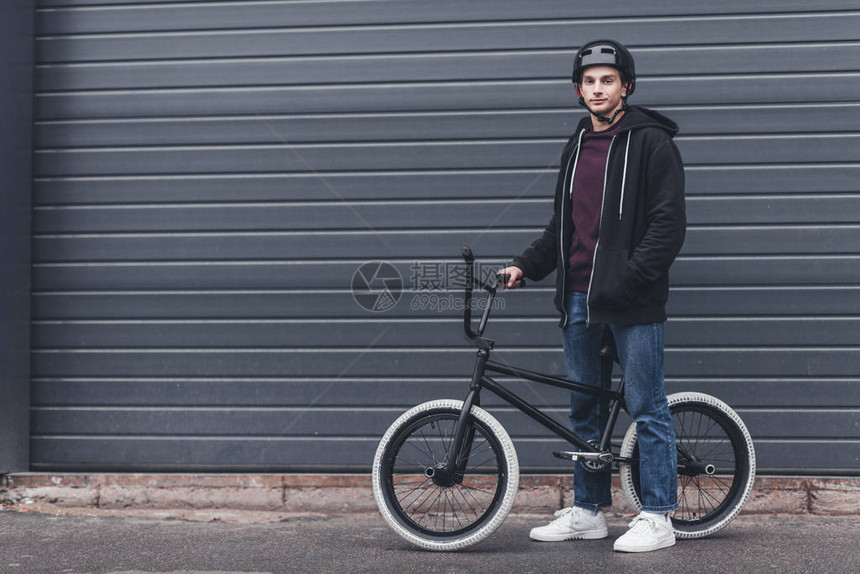 戴头盔的青年男子站在bmx自行车旁边看图片