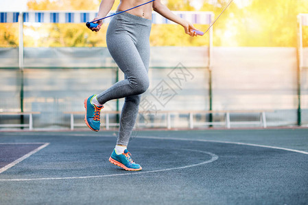 在体育场上使用跳绳的年轻运动妇女低图片