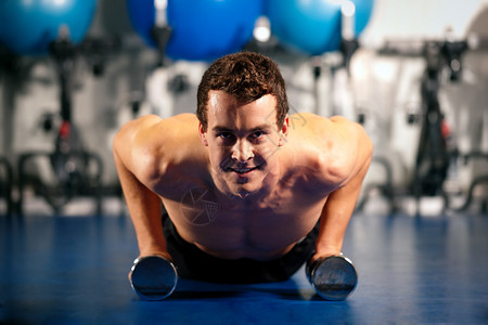 在健身房的哑铃上做俯卧撑作为健体锻炼练习图片