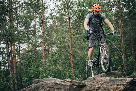 戴防护头盔的男骑自行车男子在森林中执行山图片