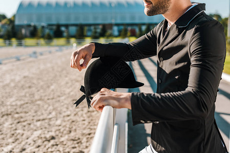 男骑马者在马俱乐部戴头盔靠在栅栏上挂着头盔的男背景图片