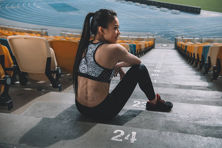 坐在体育场楼梯上和休息操跑妇女疲累概念的劳累图片