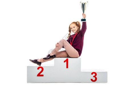 微笑的女学生坐在获胜者的领奖台上图片