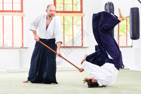 在武术学校Aikido训练中用木棍打斗图片