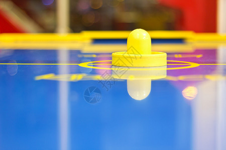 蓝色空气曲棍球桌上的黄色空气曲棍球槌图片