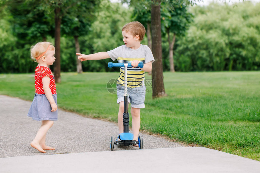 两个白种人学龄前儿童在外面的公园里打架男孩和女孩不能共用一辆滑板车哥不把玩具给妹图片