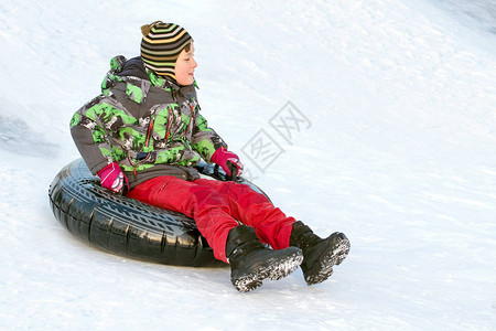 快乐的男孩与雪管冬季乐趣滑下山图片