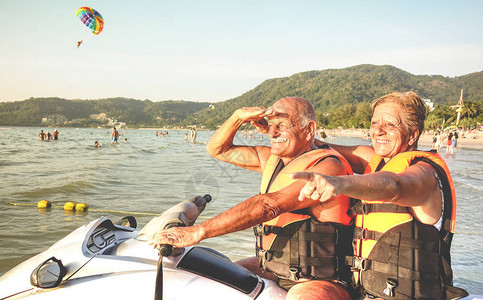 高级幸福夫妇在海滩环岛游中享受摩托艇的乐趣活跃的老年人和世界各地的旅行概念背景图片