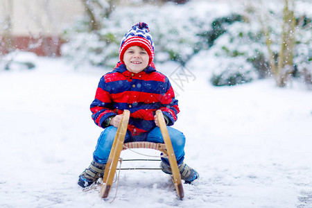 小男孩拿着雪橇学校孩子在户外玩耍在冬天的雪崩期图片