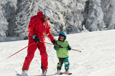 在滑雪坡个人滑雪课上与小男孩一起工作图片