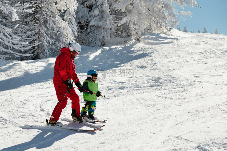 滑雪教练和斜坡上的小男孩图片