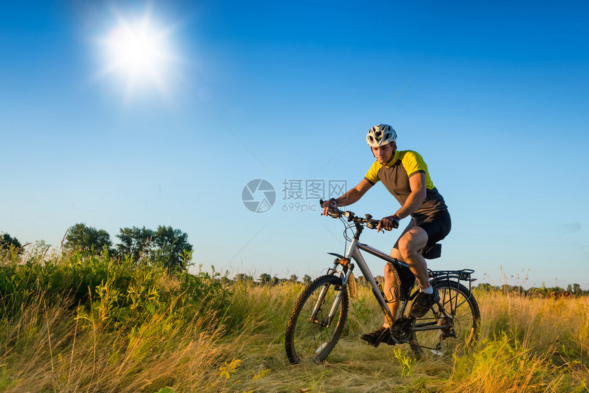 在草原上骑山地自行车的男人骑自行车旅行图片